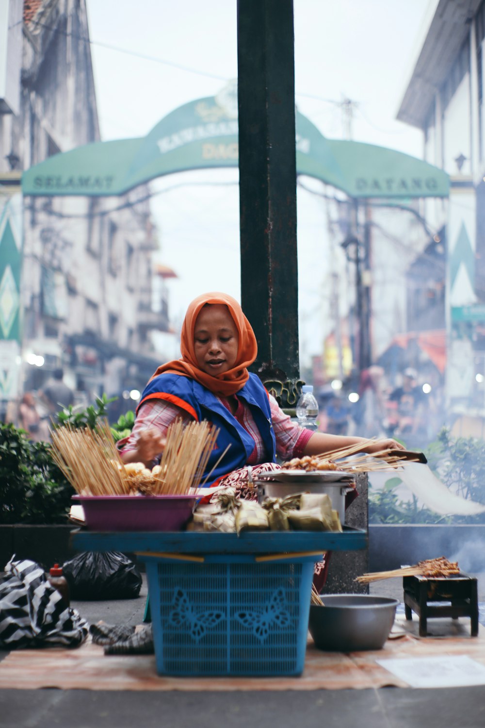 woman in blue and brown hijab sitting on red plastic crate