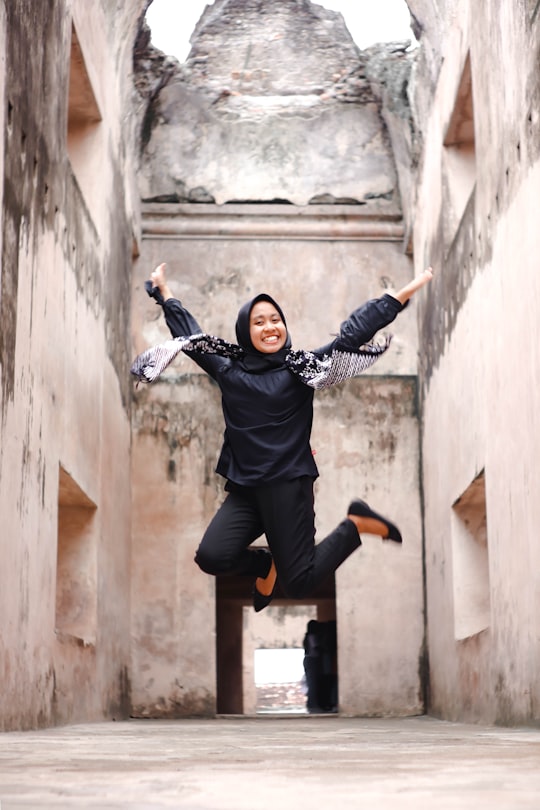 woman in black jacket and black pants jumping on gray concrete floor during daytime in Jogja Indonesia