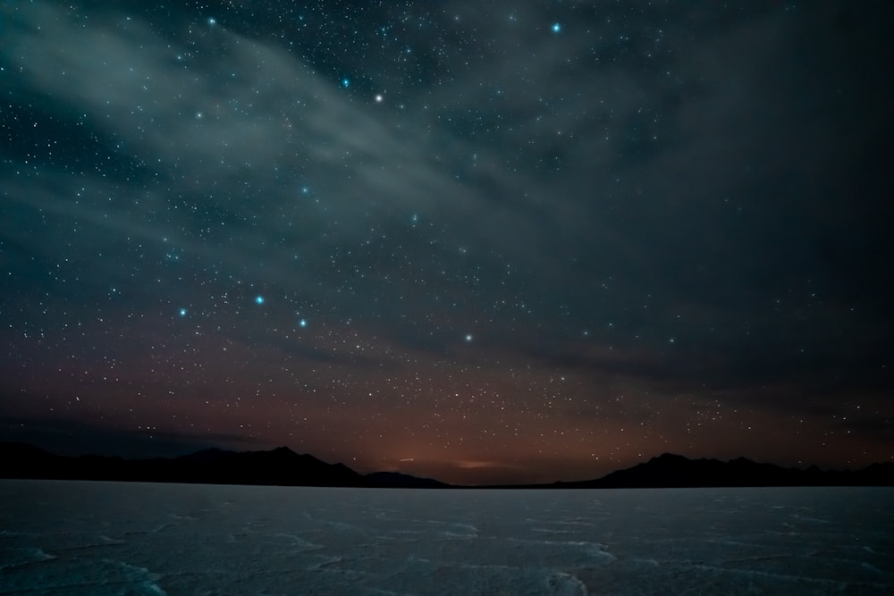 silhouette of mountain under blue sky with stars during night time