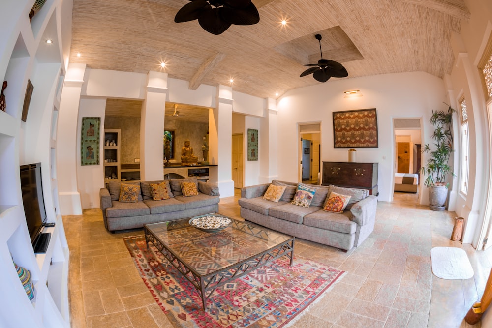 living room with gray and white floral sofa set and brown ceiling fan