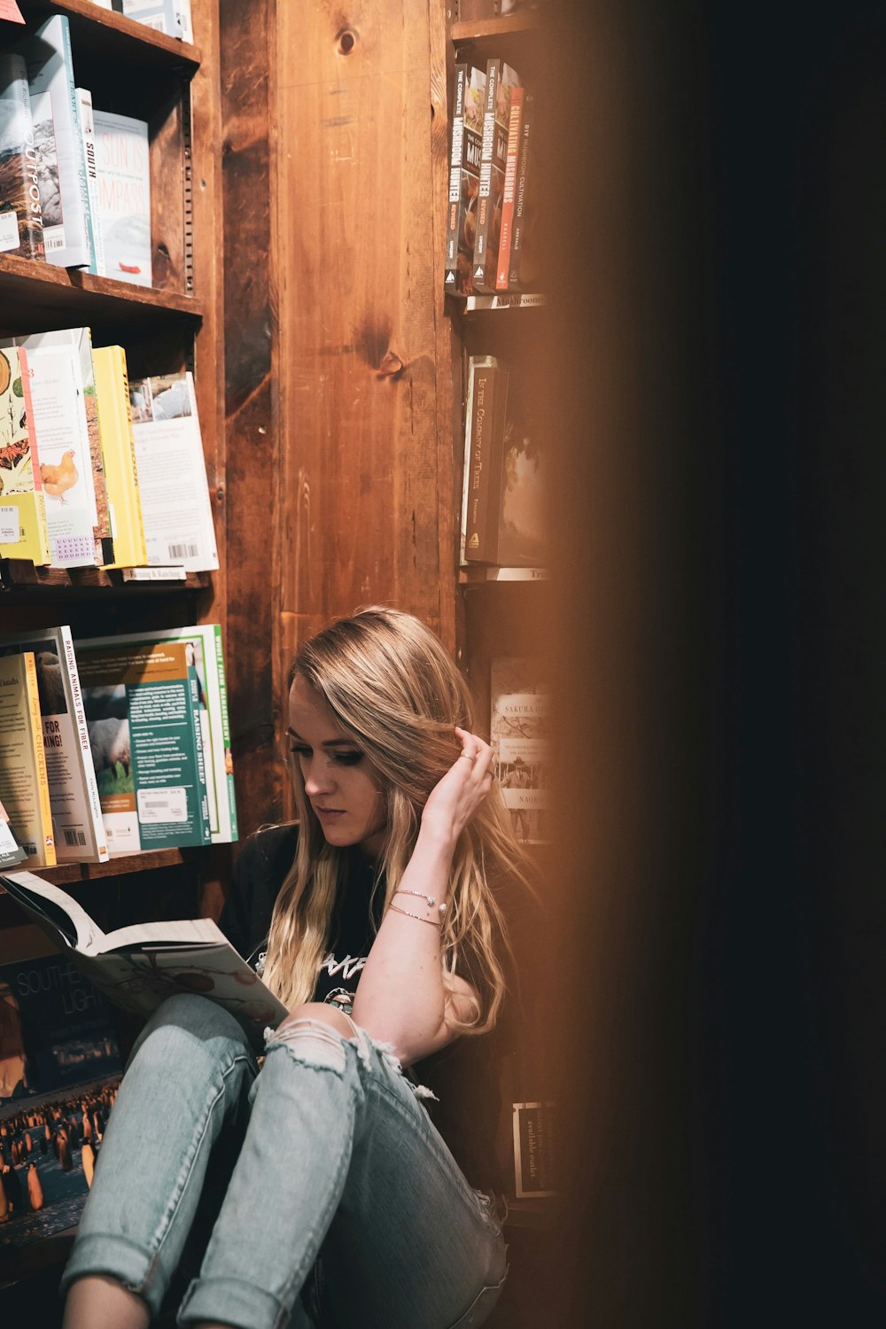 woman in white and blue floral shirt sitting beside brown wooden cabinet