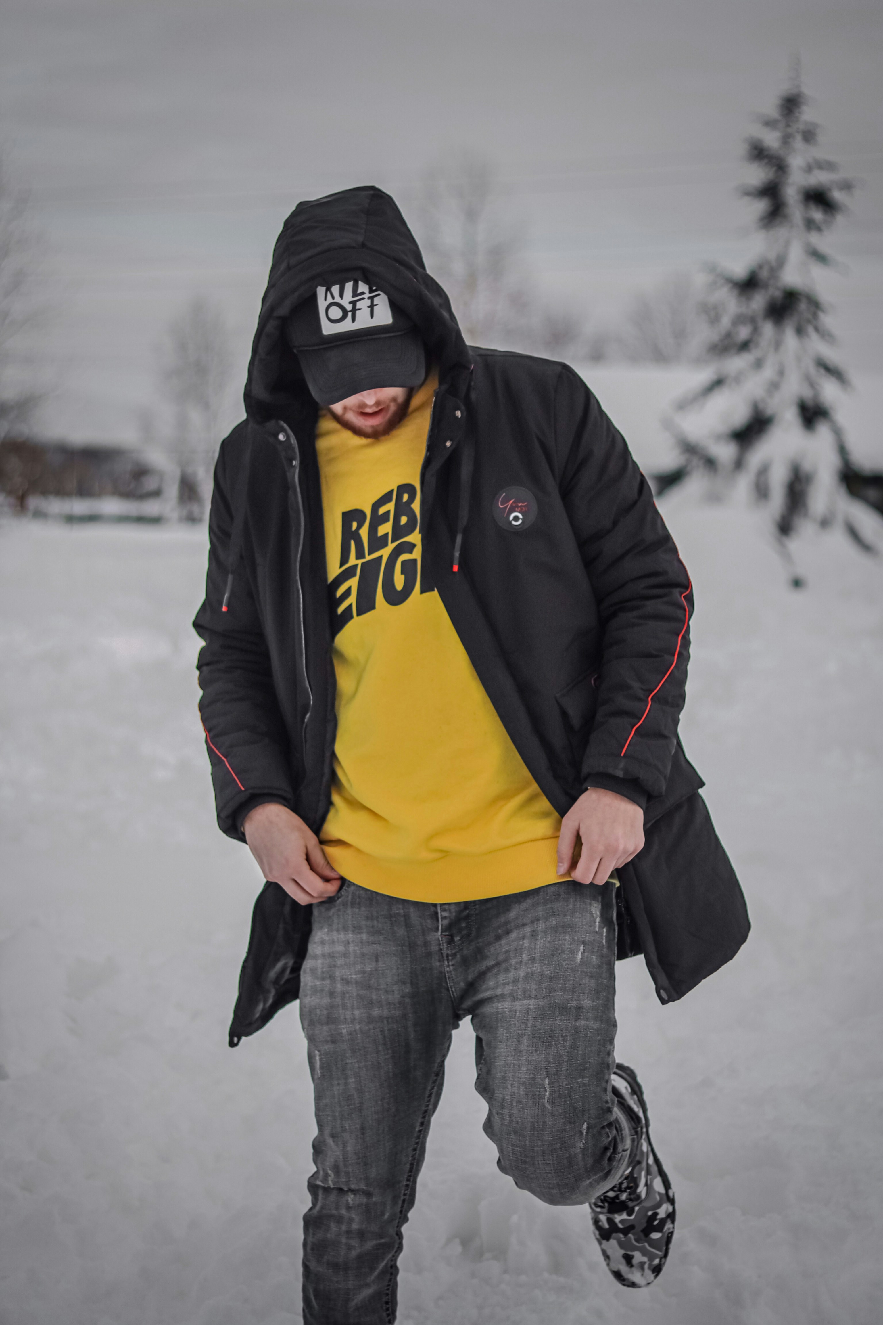 man in black jacket and yellow shirt standing on snow covered ground during daytime