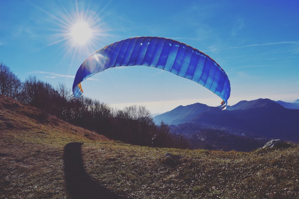 blue and white parachute over green grass field during daytime