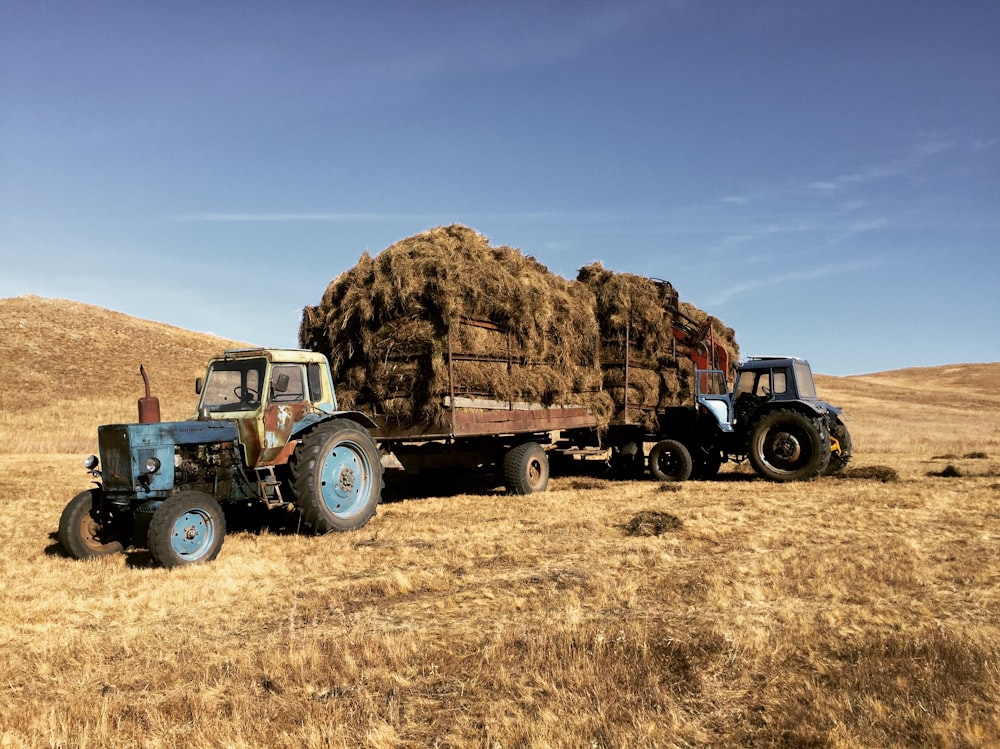 blue tractor on brown field during daytime