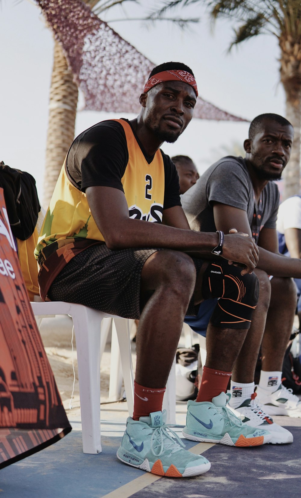 man in black and red nike jersey shirt sitting on white plastic chair