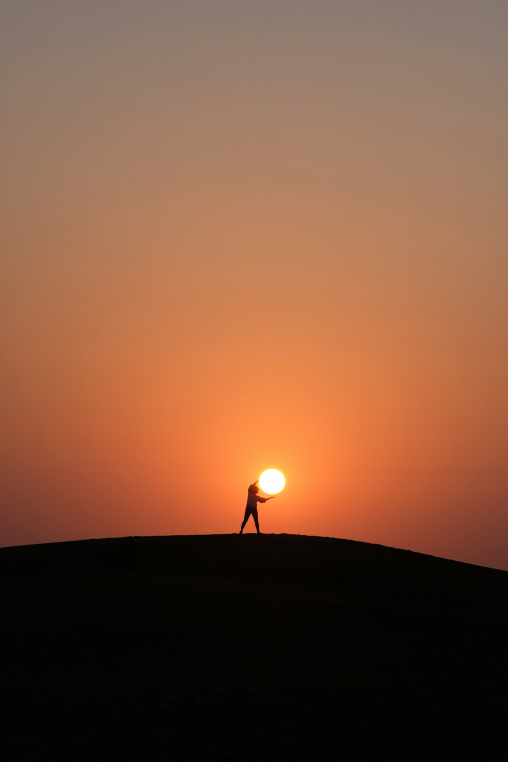 夕暮れ時の丘の上に立つ人のシルエット