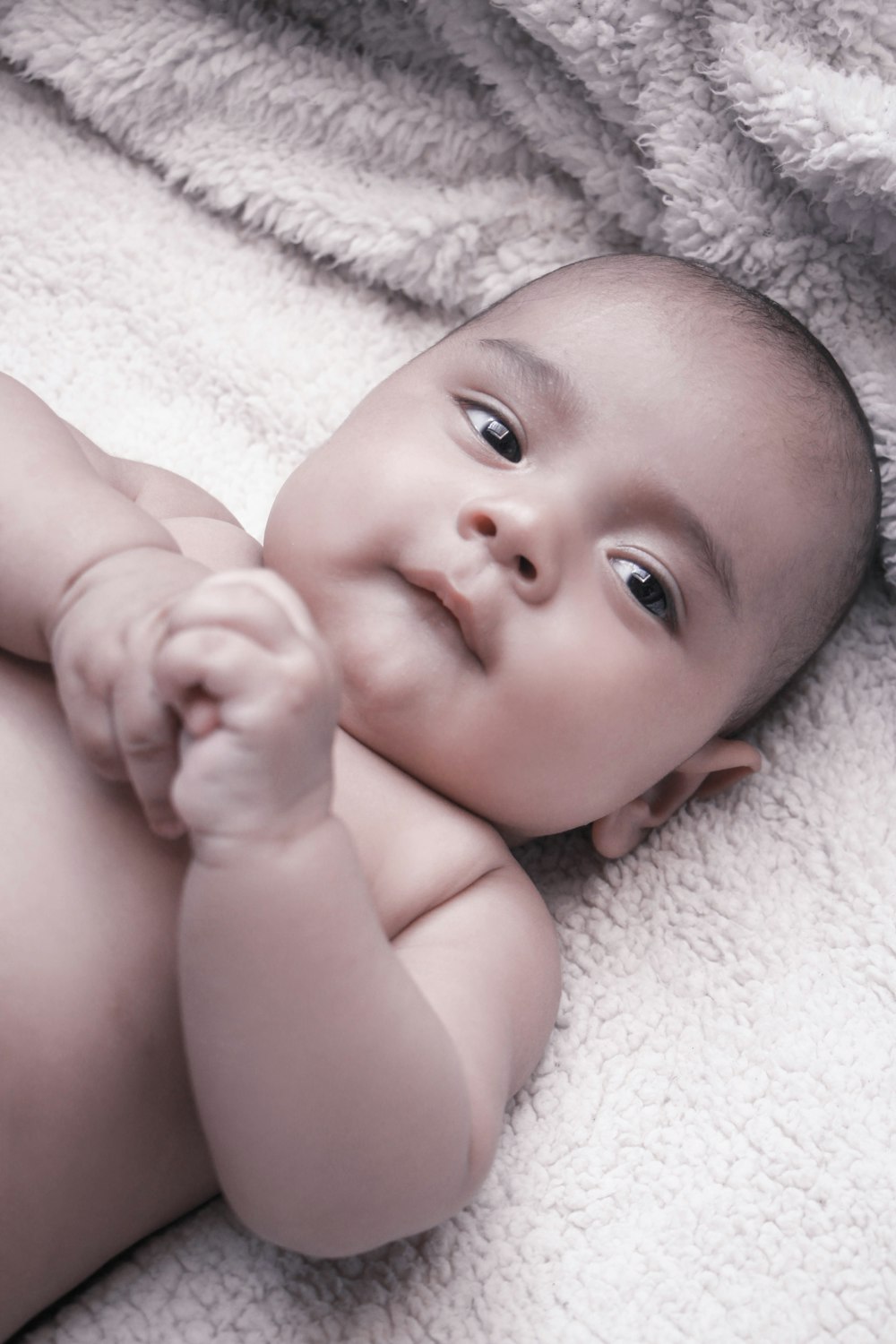 baby lying on white textile