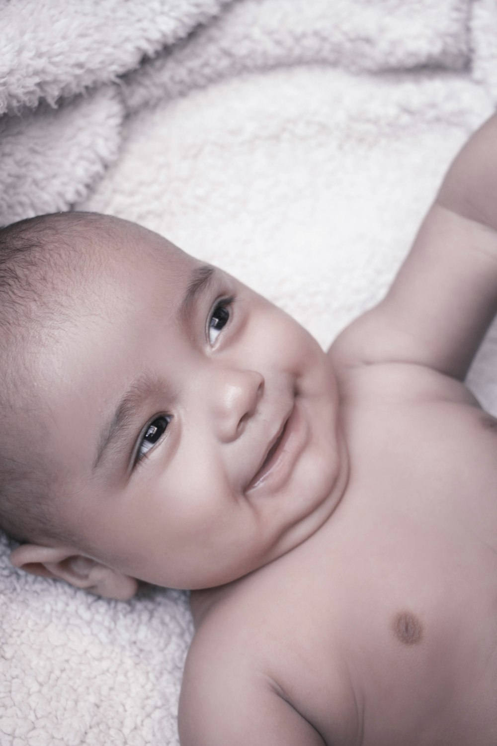 baby lying on white textile