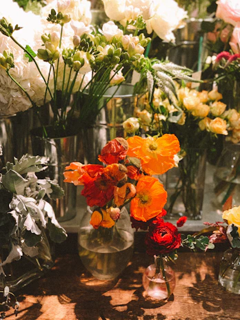 A cheerful arrangement of bright ceramic vases with fresh flowers on a wooden counter.