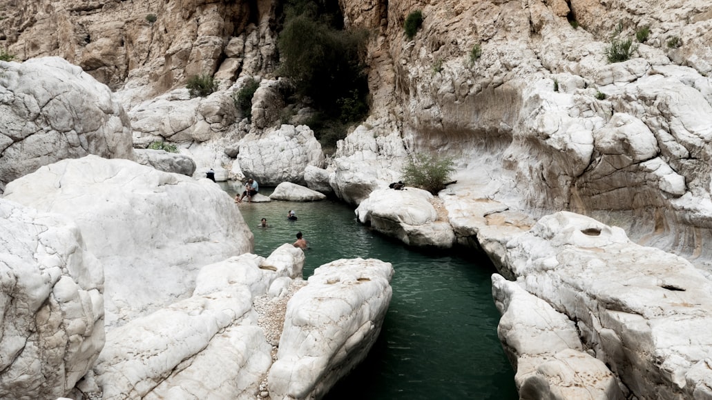 Persone fanno il bagno tra le rocce bianche del Wadi Bani Khalid