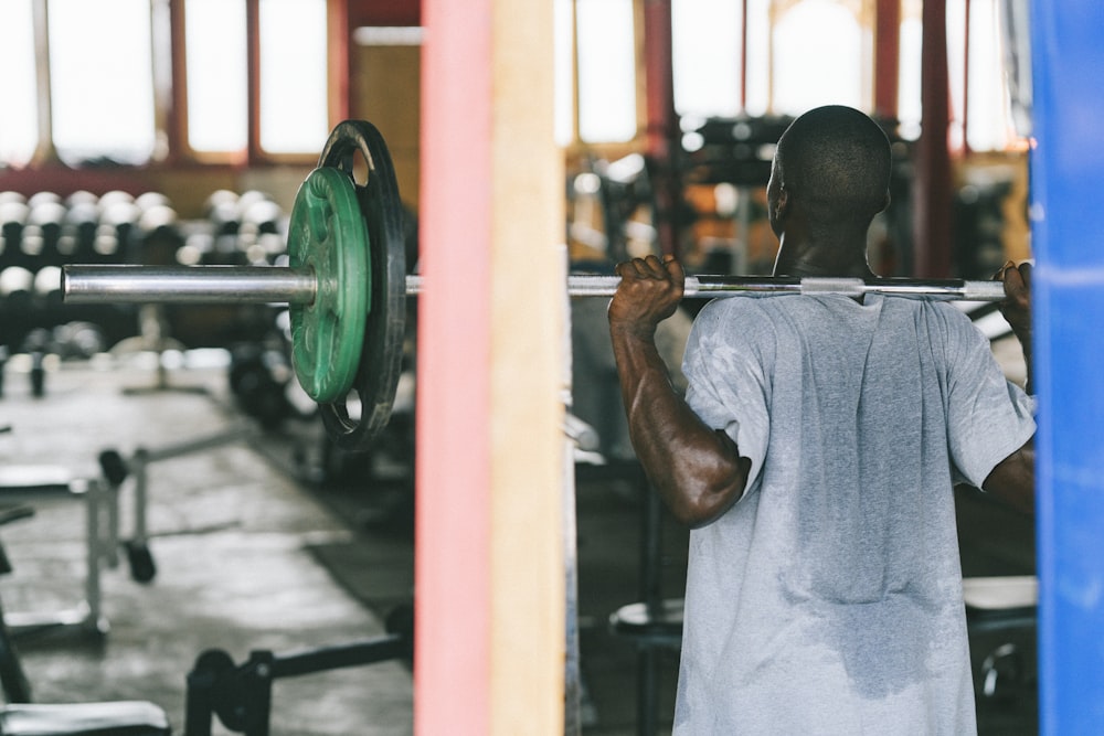 man in gray t-shirt holding green dumbbell