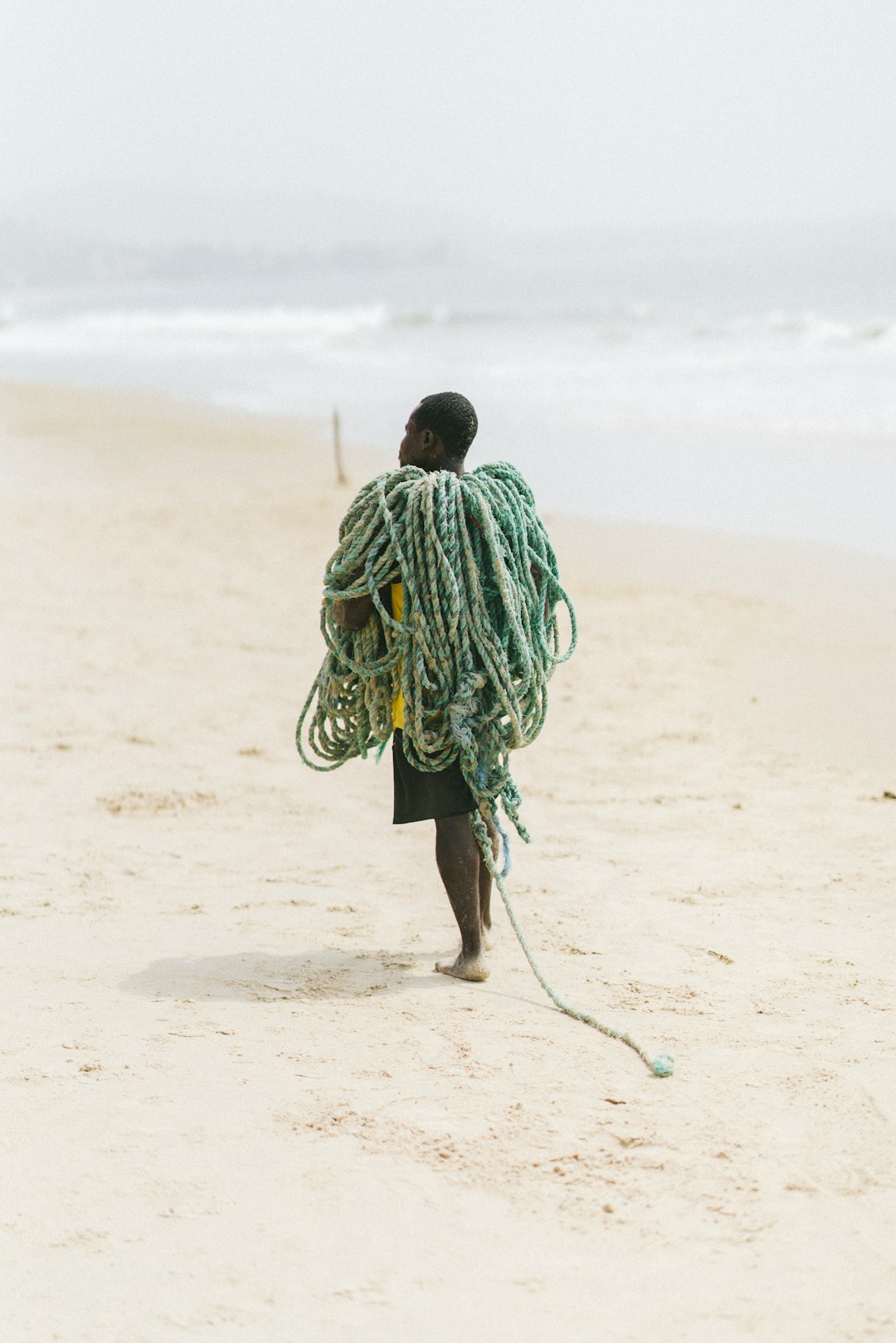 man in green and white stripe hoodie walking on brown sand during daytime