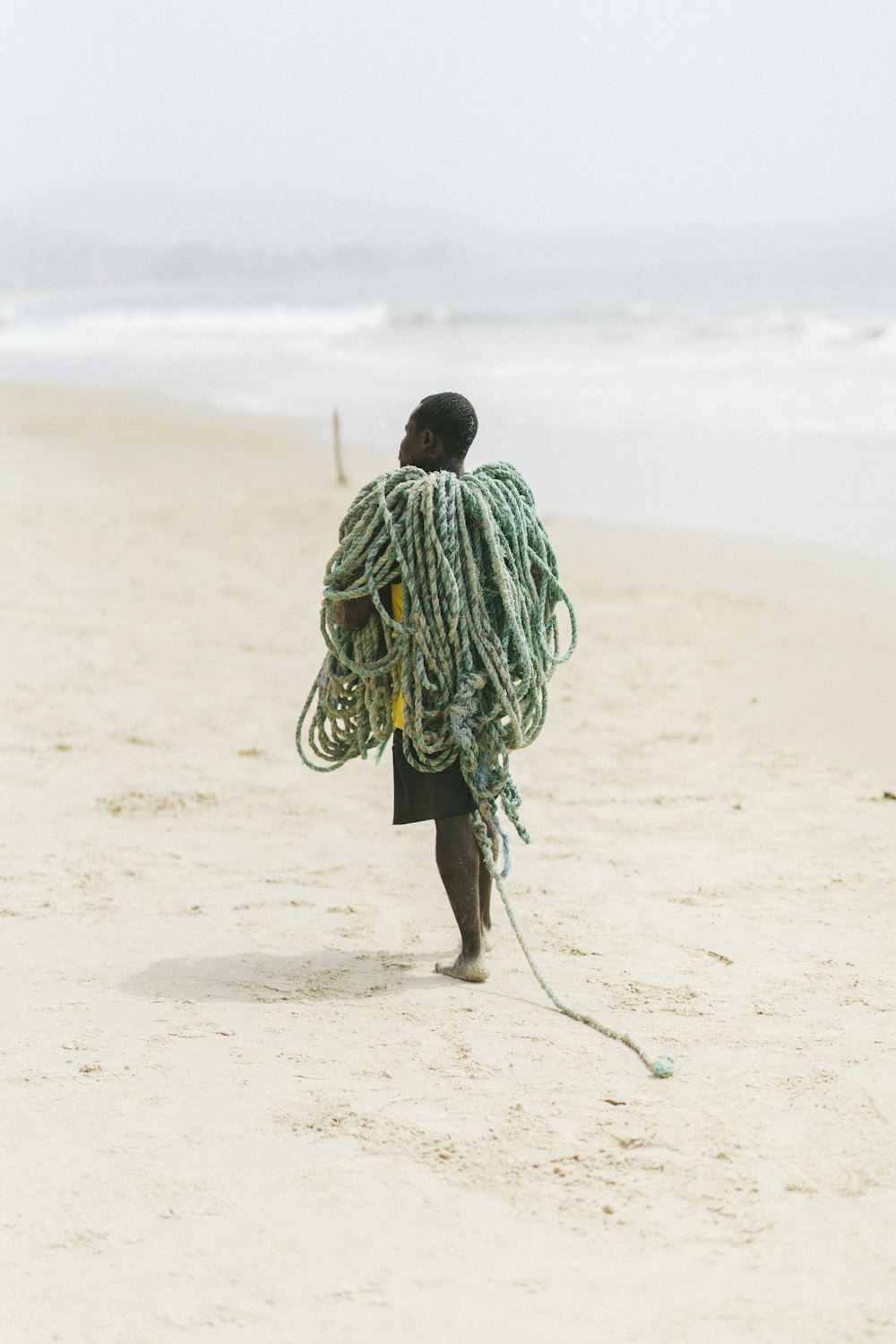 homme en sweat à capuche à rayures vertes et blanches marchant sur le sable brun pendant la journée