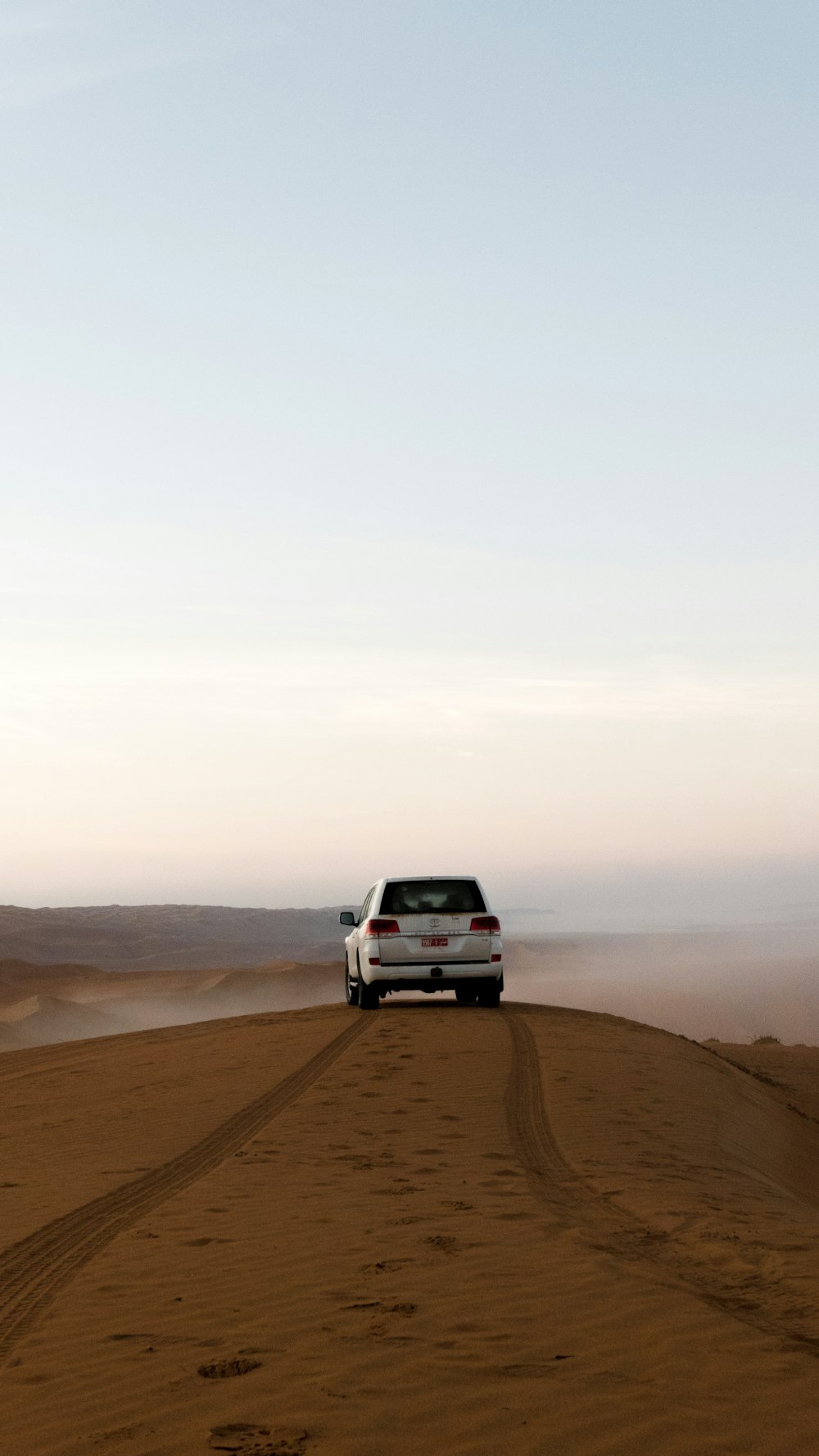 갈색 모래 위의 흰색 SUV