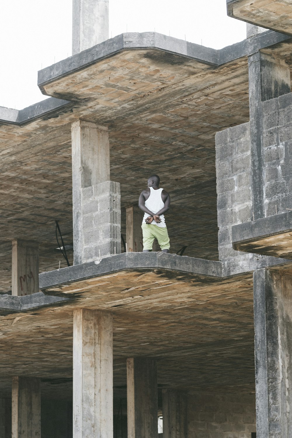 man in white t-shirt and black pants sitting on concrete wall during daytime