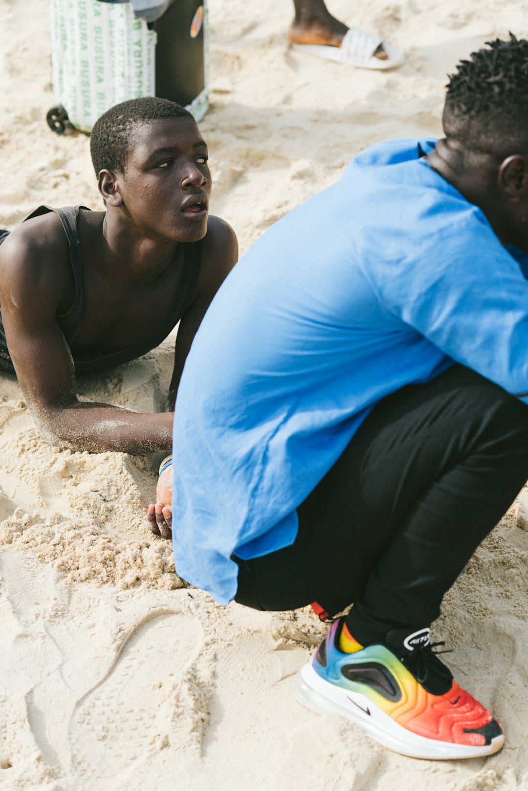 man in blue shirt and black pants sitting on sand