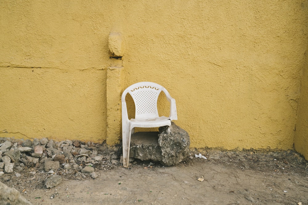 white plastic armchair beside brown concrete wall