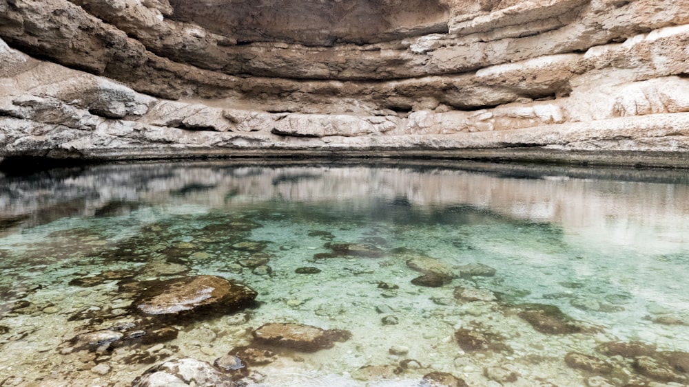 Formación rocosa marrón junto al cuerpo de agua durante el día