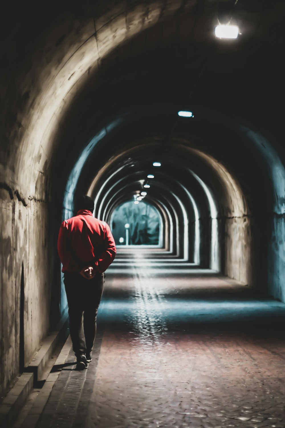 person in red hoodie walking on tunnel