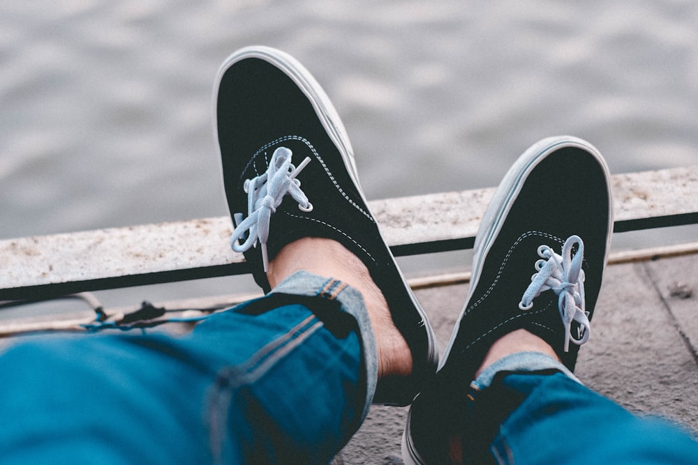 person in blue denim jeans wearing black and white sneakers