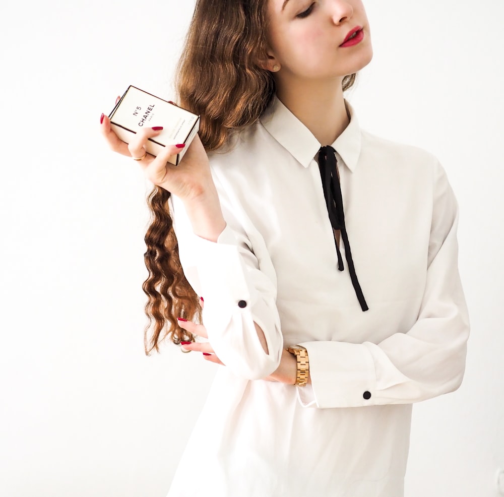 woman in white blazer holding white smartphone