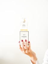 Hands holding a beautifully wrapped perfume box with a subtle red ribbon.