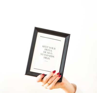 person holding black framed white arabic text