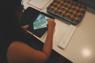 A close-up of hands working on a digital tablet creating social media graphics with bright, engaging colors.