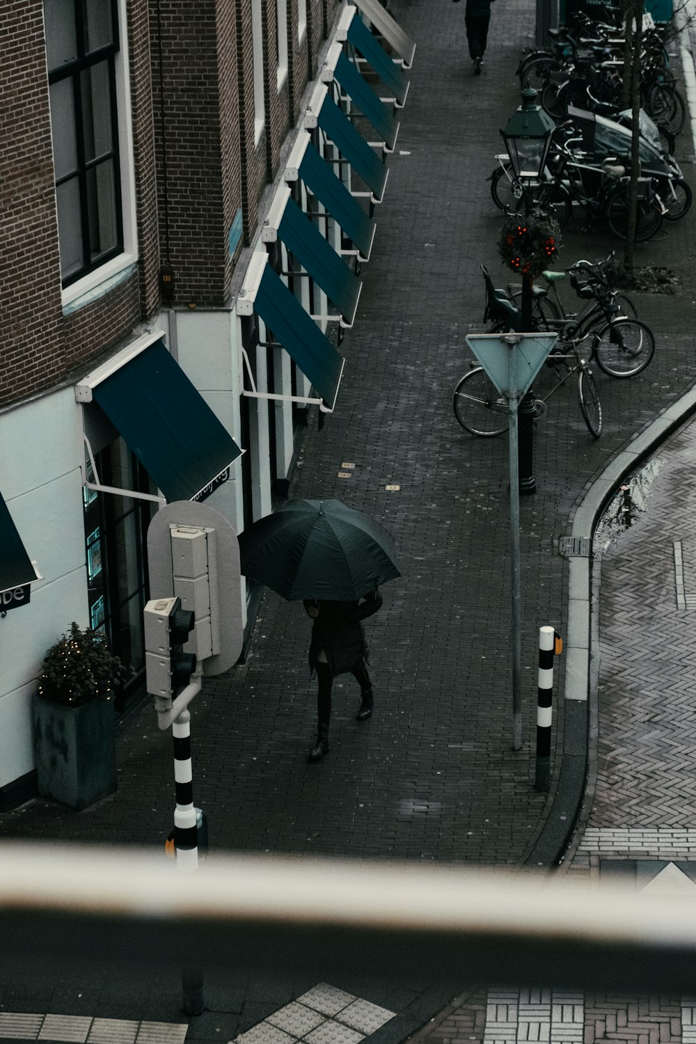 person in black jacket holding umbrella walking on sidewalk during daytime