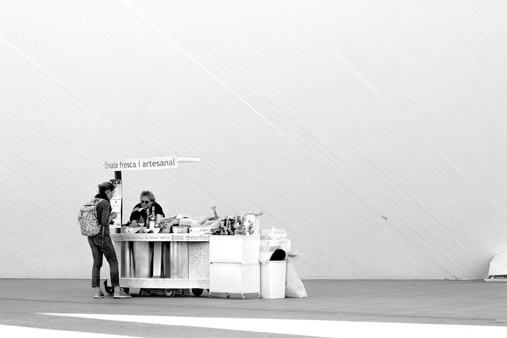 grayscale photo of people standing near table