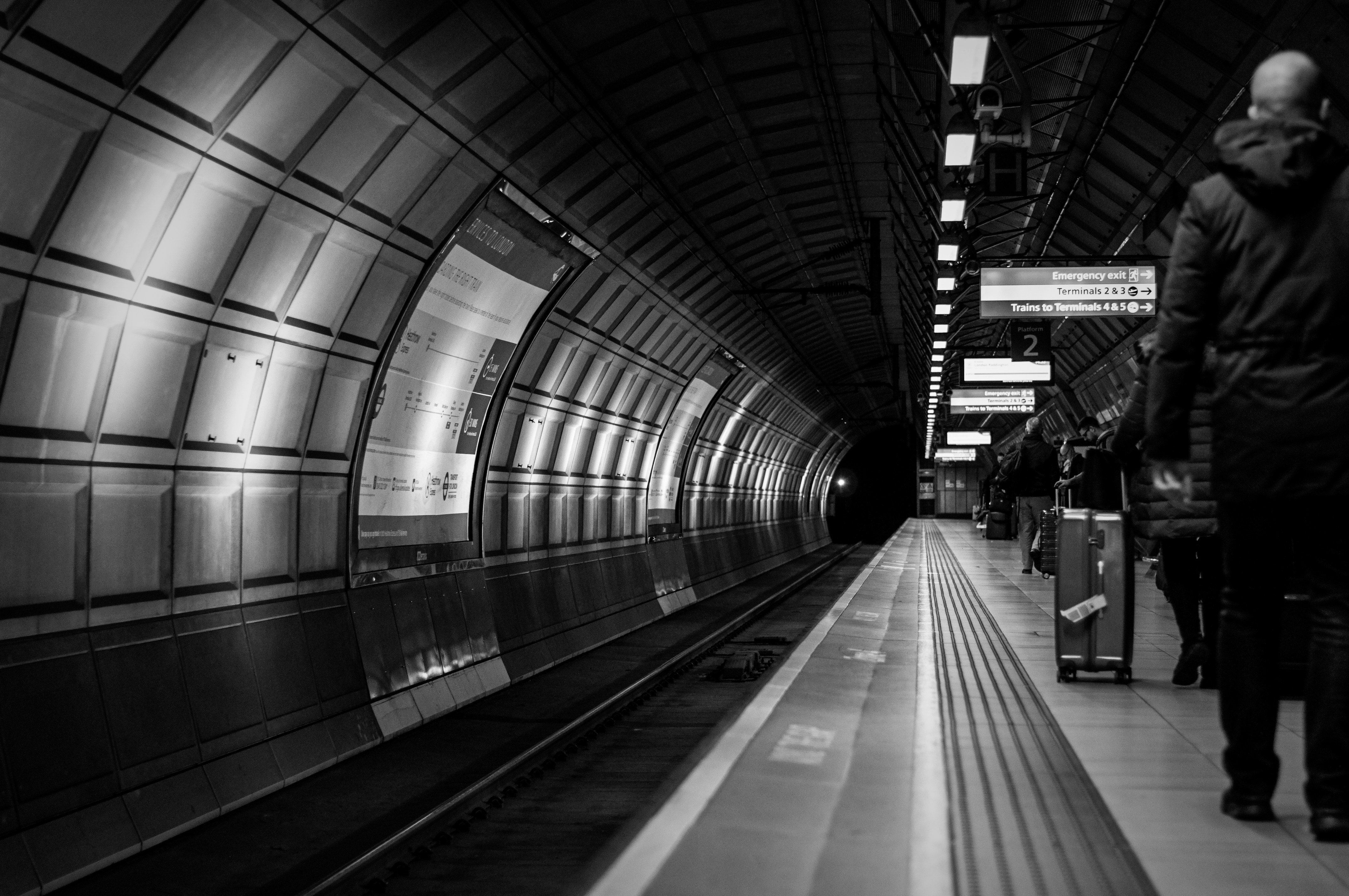 grayscale photo of people walking on train station, Heathrow, London