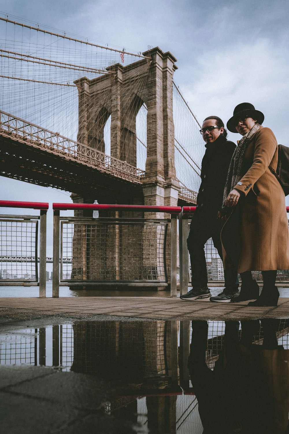 man and woman standing on bridge during daytime