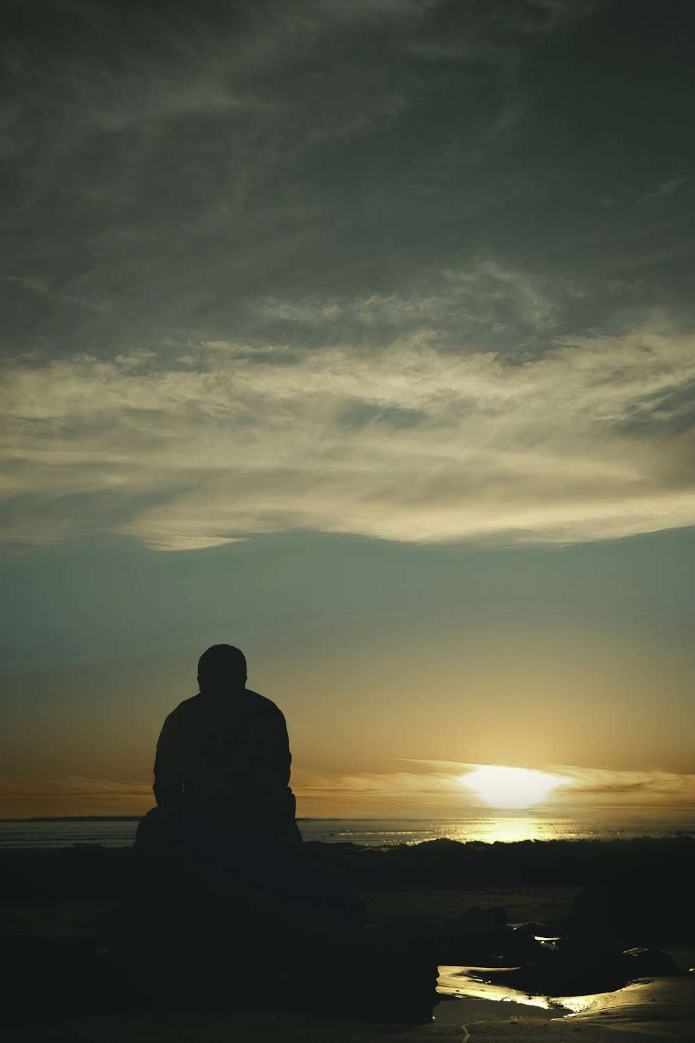 Silhouette eines Mannes, der während des Sonnenuntergangs an der Küste steht