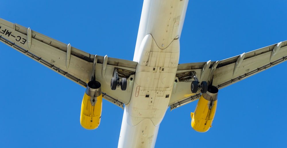 Avión blanco y amarillo bajo el cielo azul durante el día