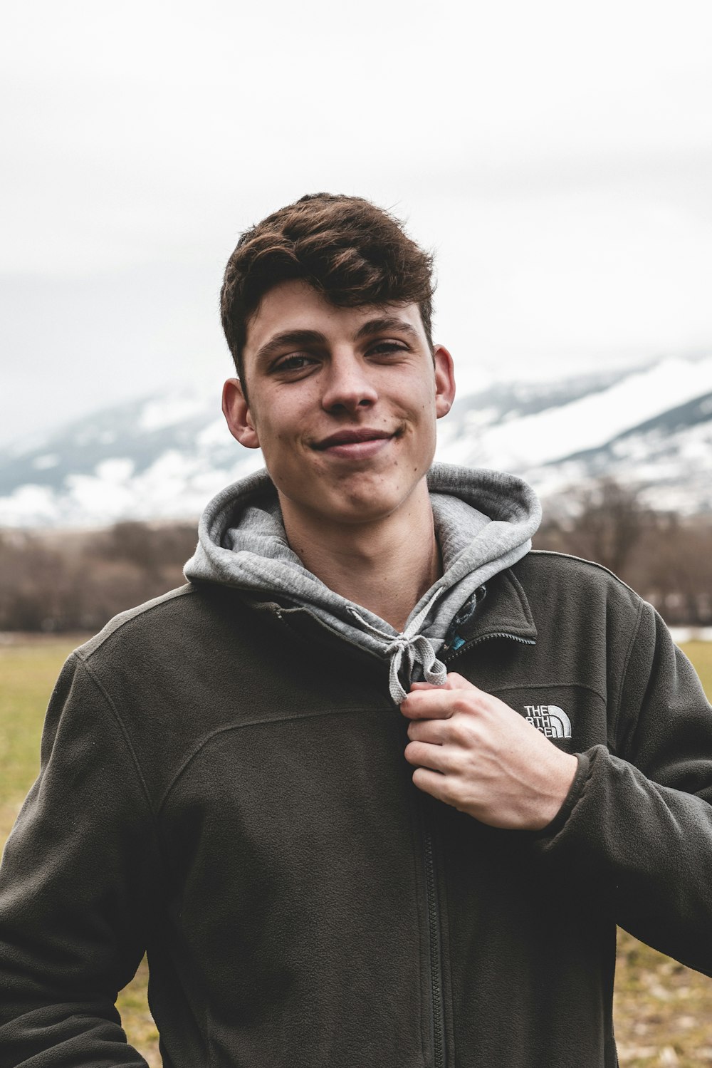 man in gray hoodie standing on green grass field during daytime