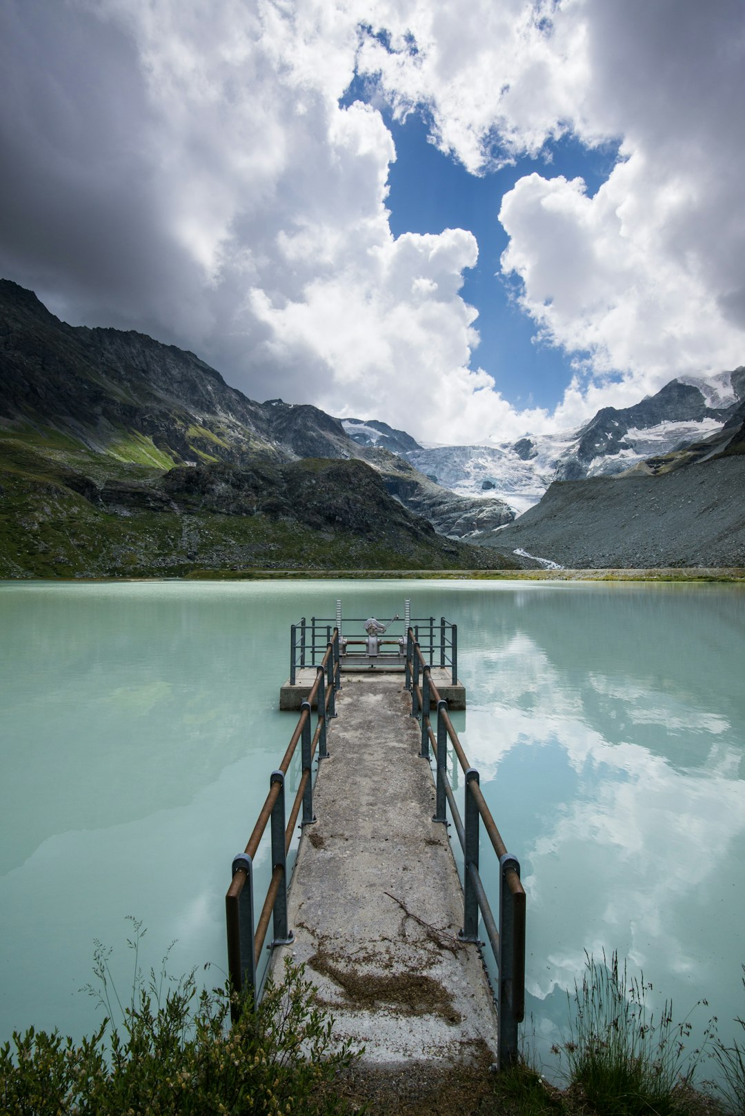 brown wooden dock on lake near green mountains under white clouds and blue sky during daytime