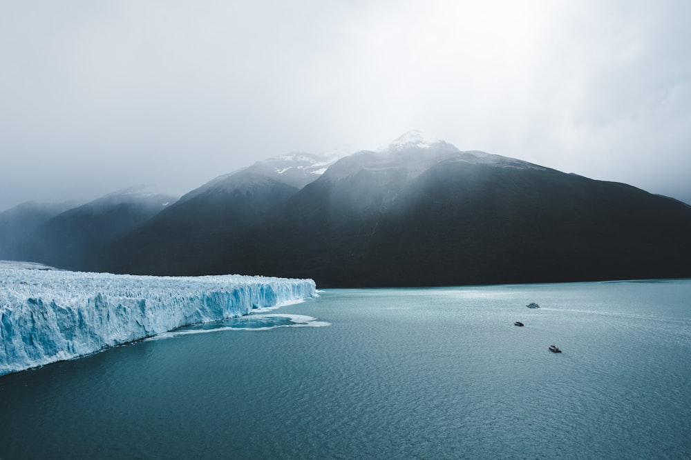 body of water near mountain during daytime