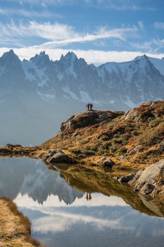 person standing on brown rock formation near lake during daytime in Chamonix France