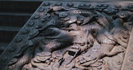 A detailed stone carving of a dragon with intricate patterns and flowing lines. The carving is skillfully executed, showing the dragon's scales, claws, and fierce expression, set against an ornate background that adds depth and complexity.