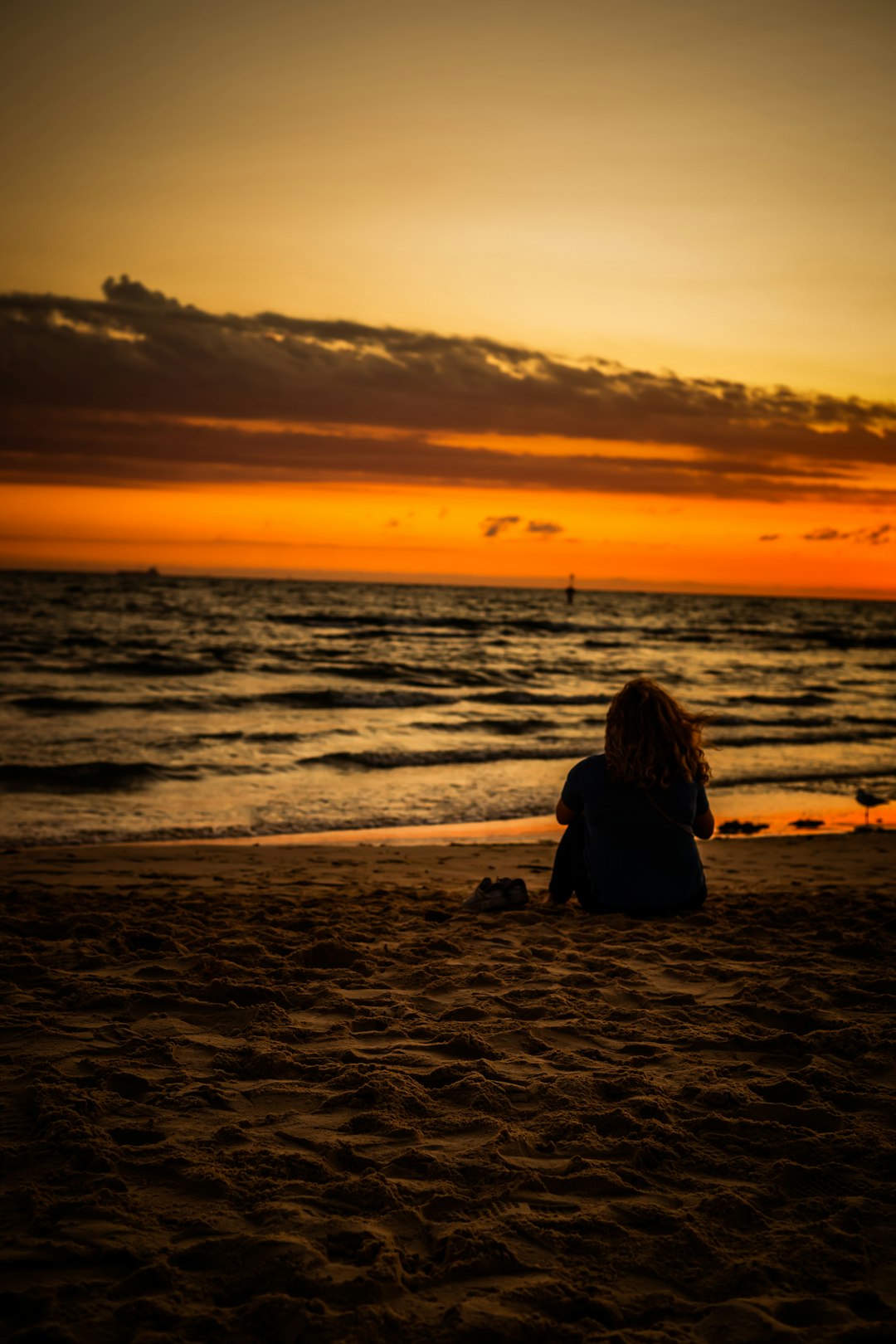 woman sitting on beach during sunset