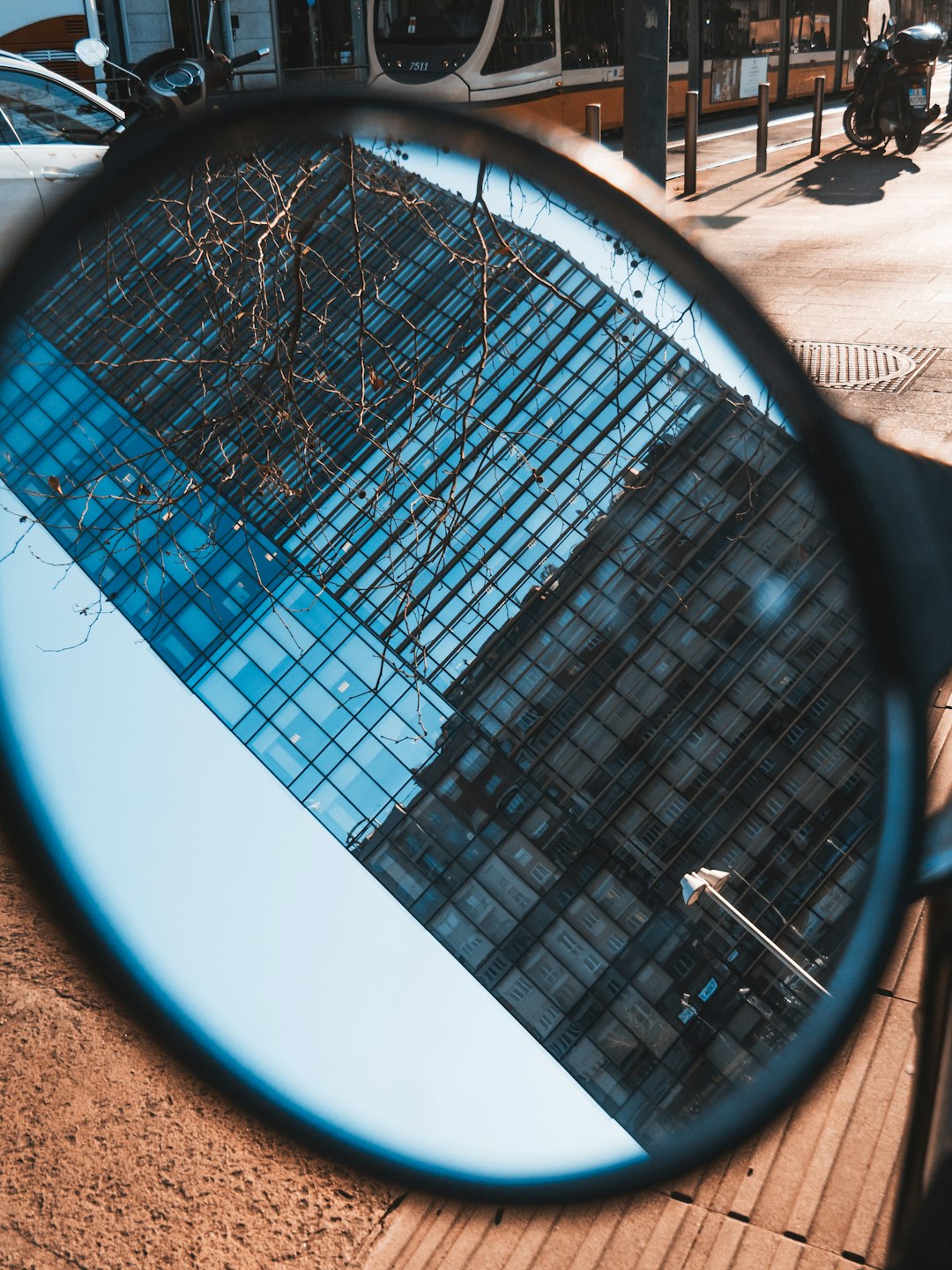 black framed round mirror reflecting white building