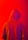 A person wearing a hooded sweatshirt with the words 'fear of god' printed repeatedly across the fabric. The background is a vivid red color, creating a striking contrast with the purple and orange hues of the hoodie.