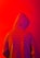 A person wearing a hooded sweatshirt with the words 'fear of god' printed repeatedly across the fabric. The background is a vivid red color, creating a striking contrast with the purple and orange hues of the hoodie.