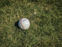 white and red baseball on green grass
