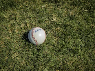 white and red baseball on green grass