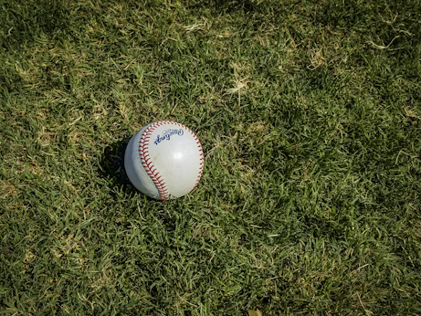 white and red baseball on green grass