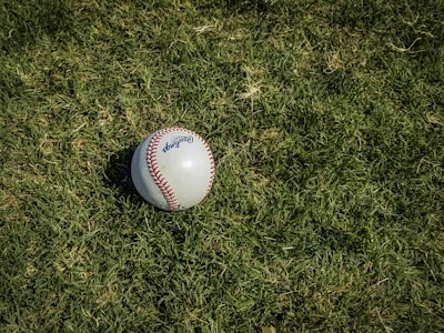 white and red baseball on green grass