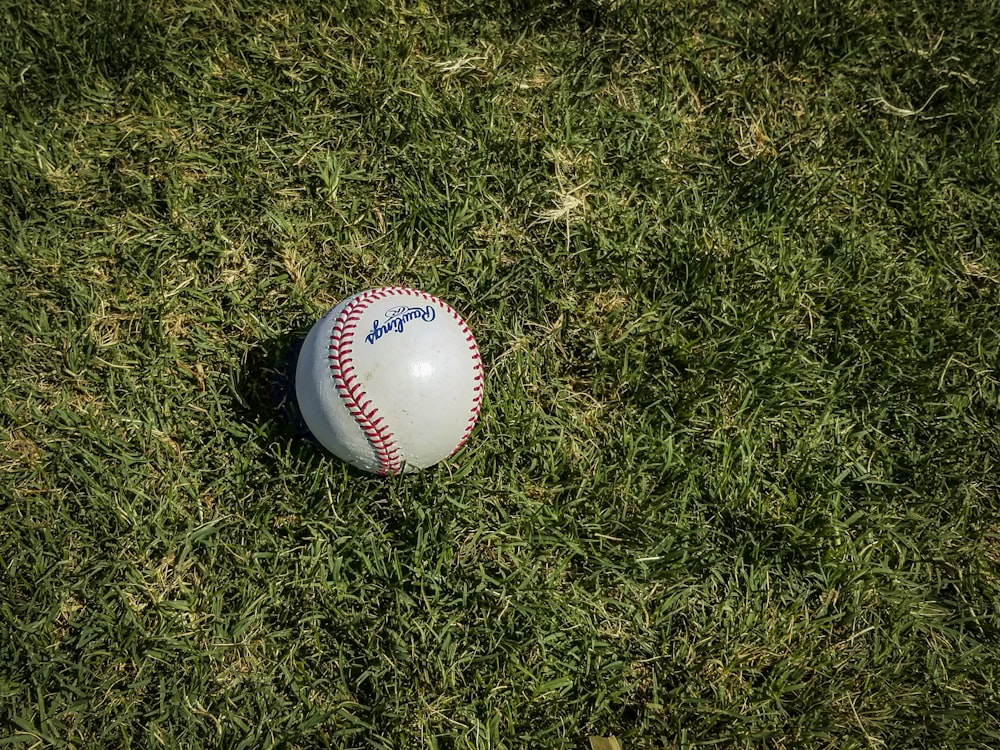 beisebol branco e vermelho na grama verde