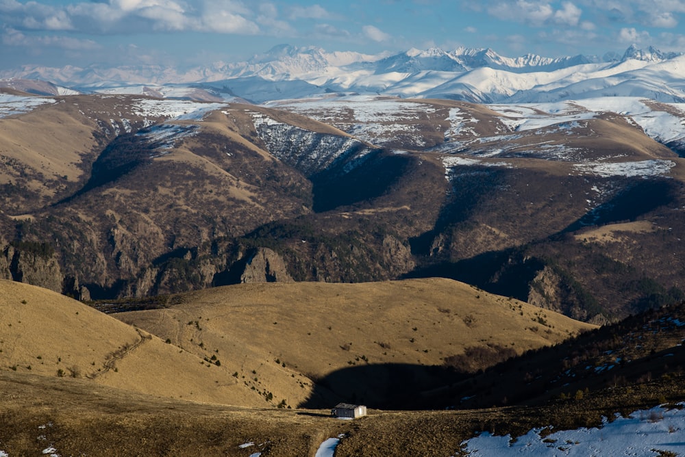 brown and green mountains under white clouds and blue sky during daytime