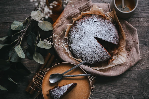 Artisanal chocolate cake with delicate frosting and a sprinkle of cocoa powder on a wooden table